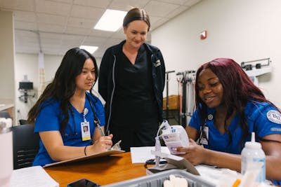 Nursing students review patient charts and data together in a Bethel University lab.