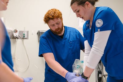 A nursing student receives guidance while performing a medical procedure at Bethel University.