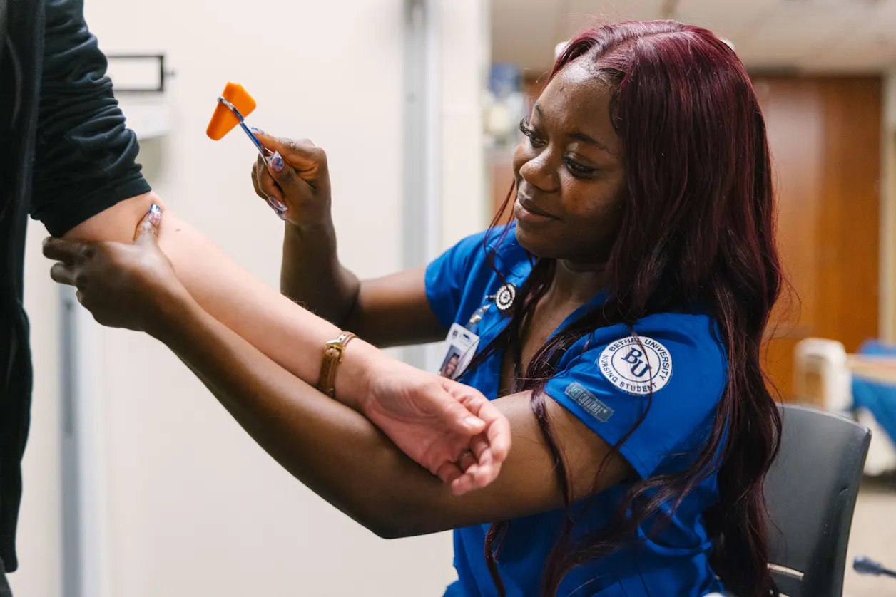 A nursing student practices reflex testing with a patient at Bethel University.