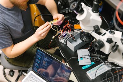 Students collaborating on an electronics project, surrounded by equipment.