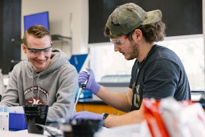 Students laughing and working together in a lab.