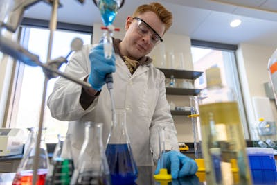 A student concentrates while working with colorful liquids in a Bethel University lab.