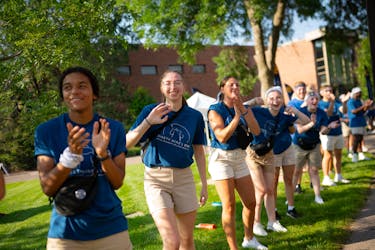 Students cheer as new students arrive on campus for the first time.