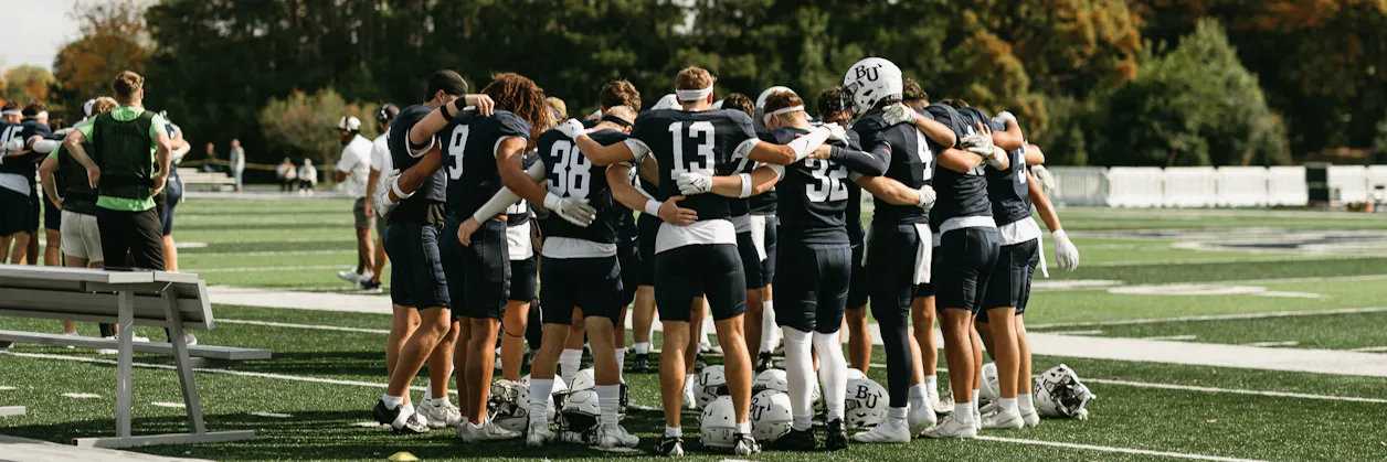 The Bethel University football team huddles up on the football field.