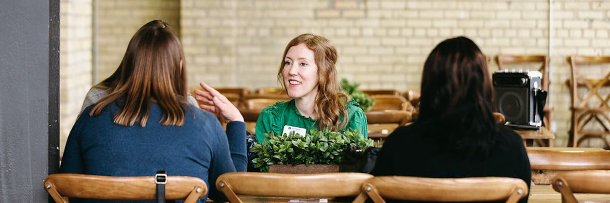Three women sit in conversation at a table during a Bethel career development or networking event.