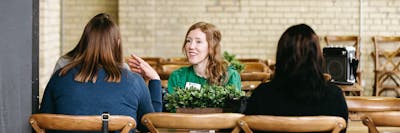 Three women sit in conversation at a table during a Bethel career development or networking event.