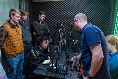 Students in blue pull hard in a competitive tug-of-war during a campus recreation event.