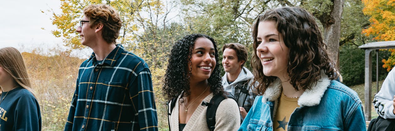 Students walk along the lakeside path at Bethel University during peak fall color