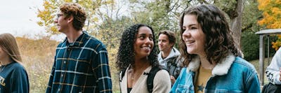 Students walk along the lakeside path at Bethel University during peak fall color