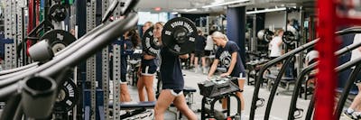Student lifts barbell while others work out in Bethel’s strength and conditioning room.