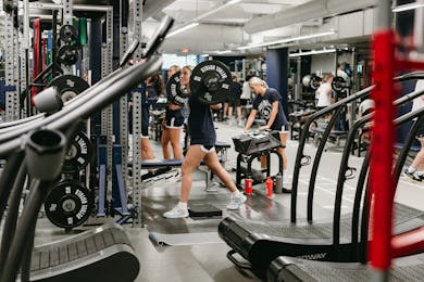 Student lifts barbell while others work out in Bethel’s strength and conditioning room.